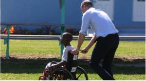 Prince William pushing a boy in a wheelchair